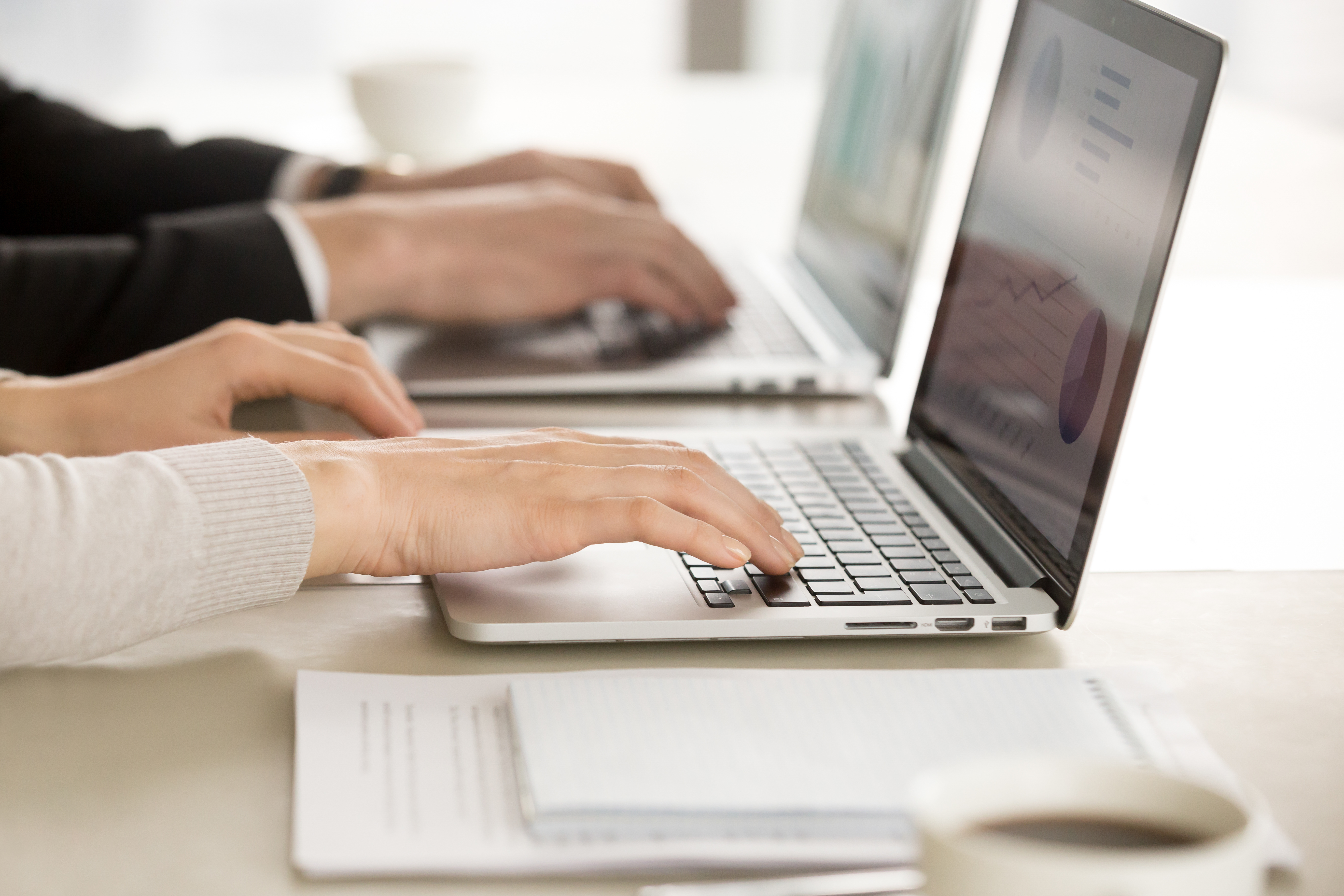 Close up image of female and male employers hands typing together on laptop keyboards at desk. Financial experts monitoring economical indicator online. E-commerce business team daily computer routine